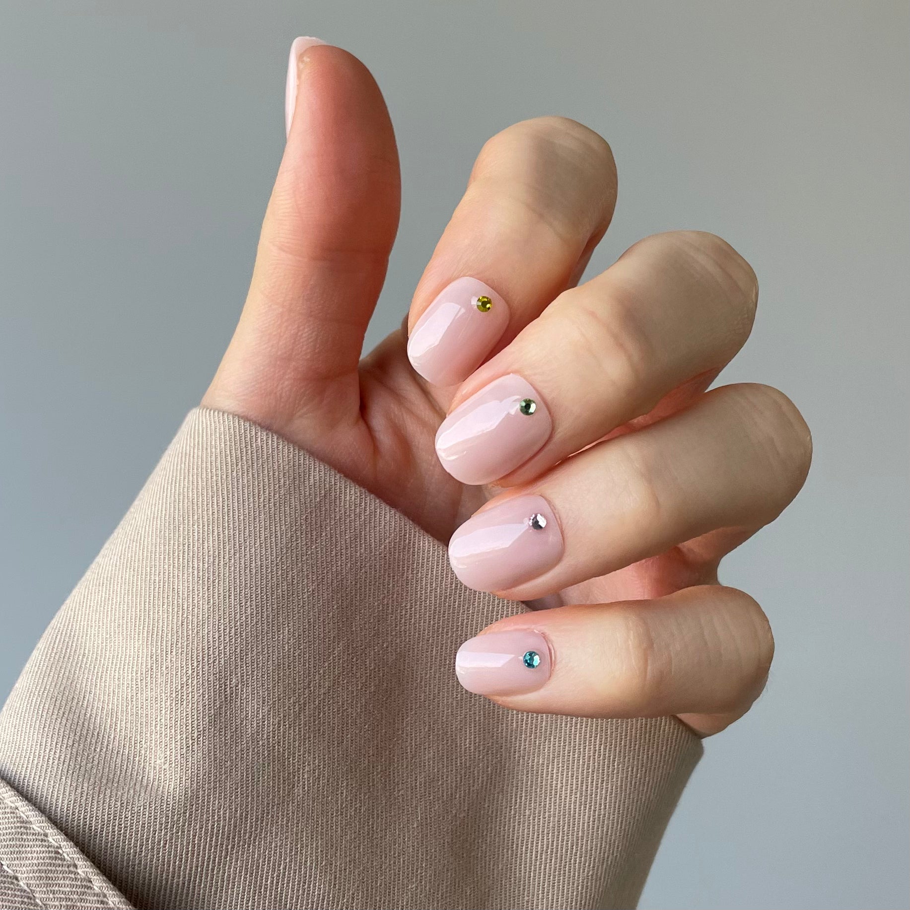 Woman's hand with salon quality acrylic nails applied at home. Pink false nails with gems. Salon quality.