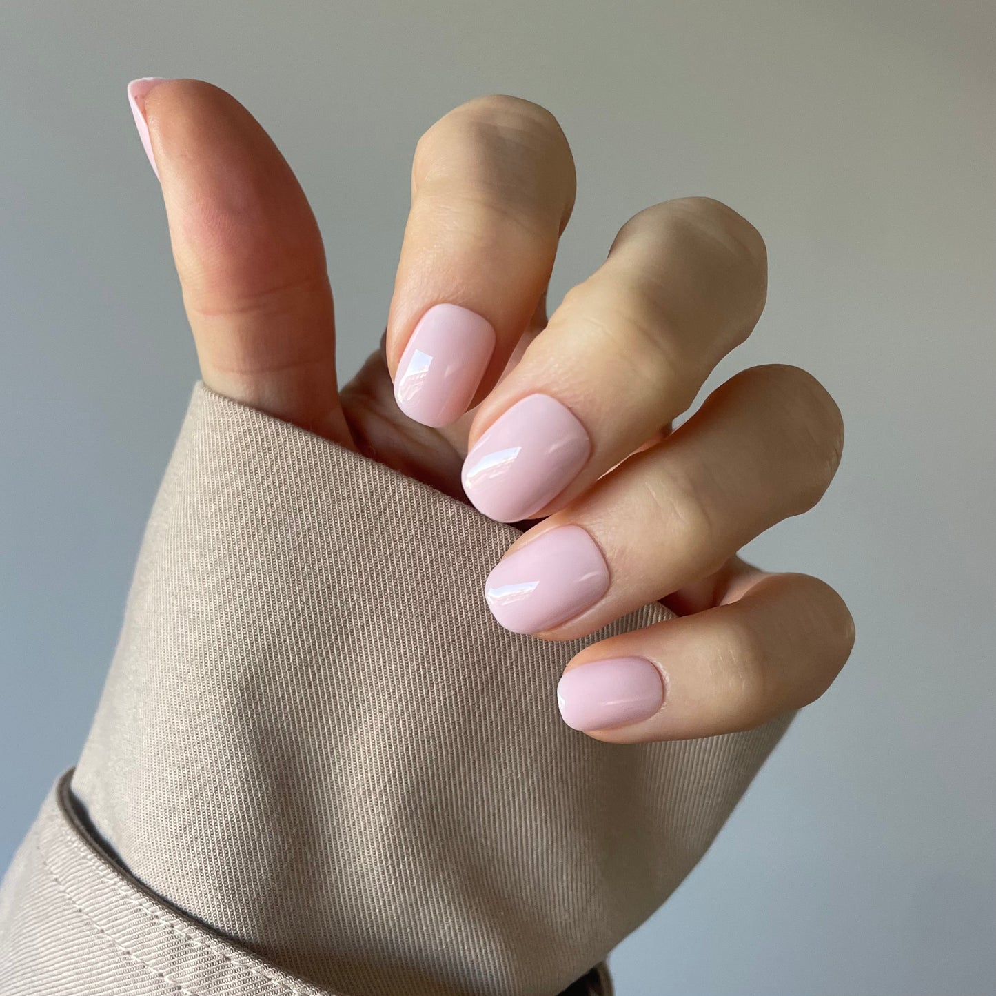 Womans hand with Candy Claws pillow talk press-on acrylic nails in the palest pink extra-short style