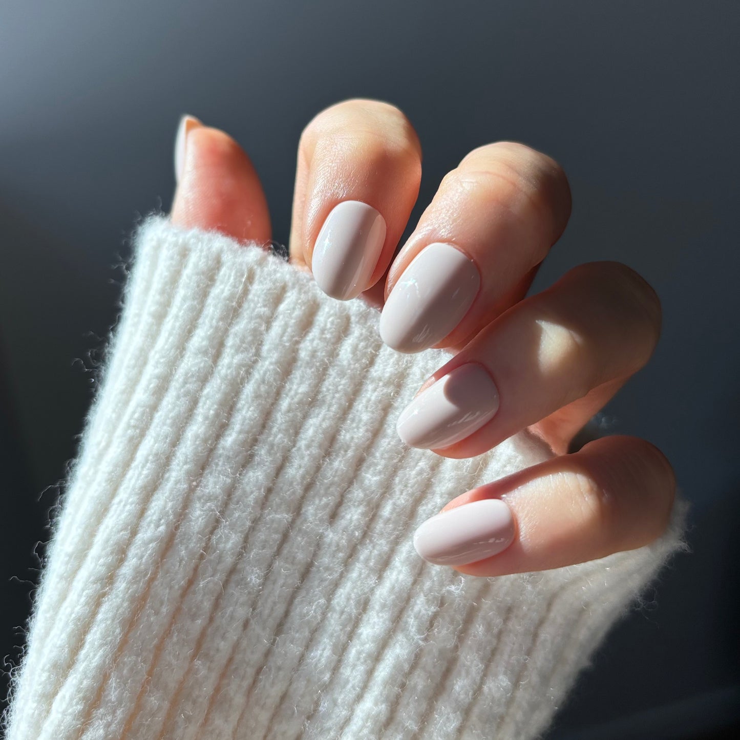 Womans hand showing short oval style press-on nails in Candy Claws vanilla crema colour