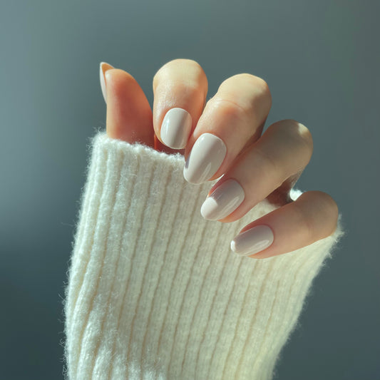 Womans hand with pale crema press on Candy Claws acrylic nails in vanilla creamy colour