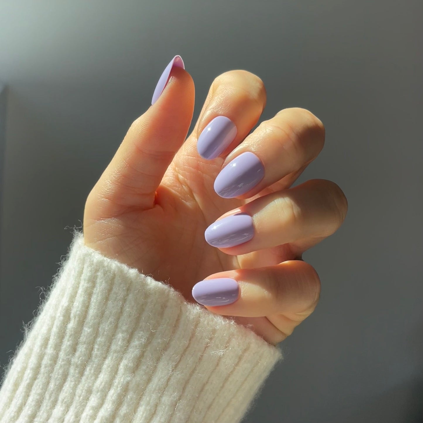 Womans hand with purple lilac false press-on salon quality nails