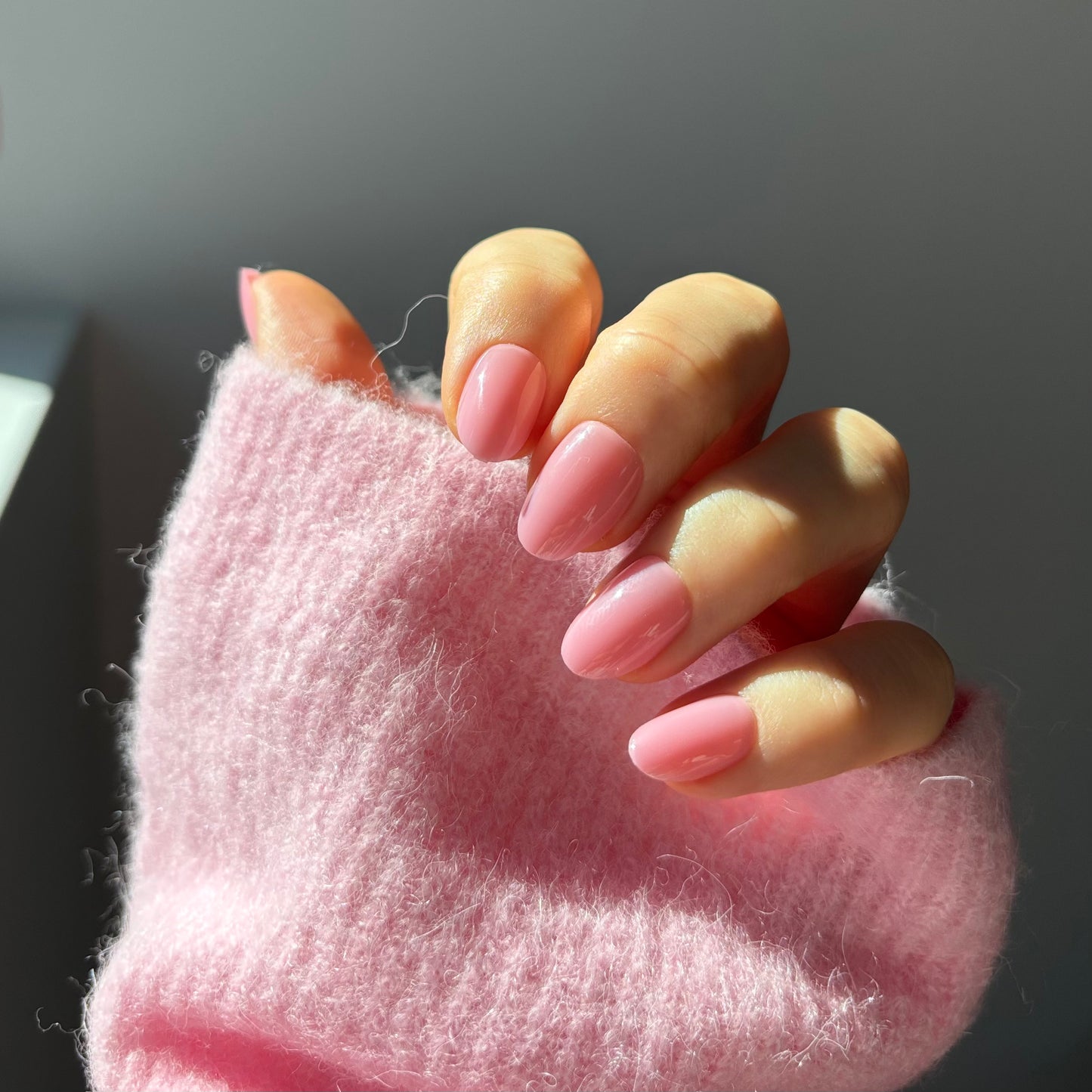 Womans hand with mid-pink short press-on Candy Claws nails. Salon quality, reusable, removable