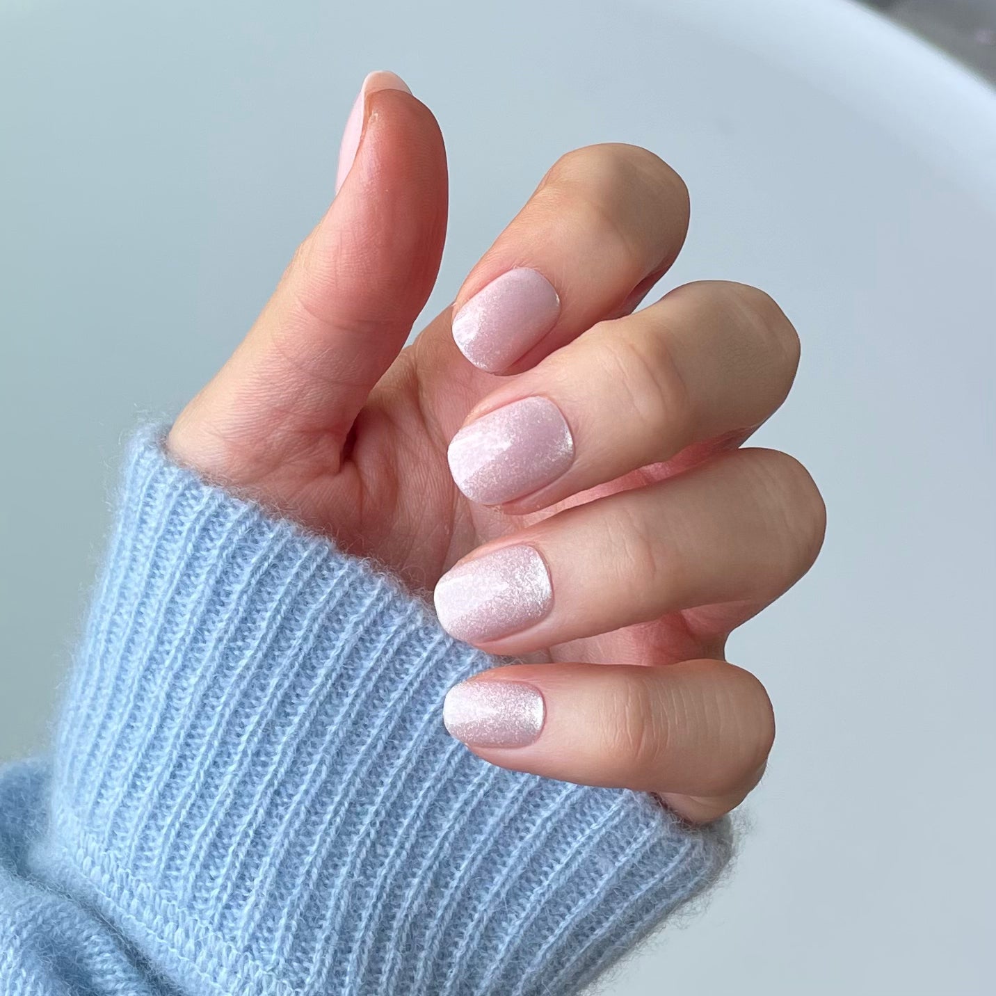 Classic bare minimum extra short press on acrylic nail with a glitter injection from Candy Claws on a womans hand